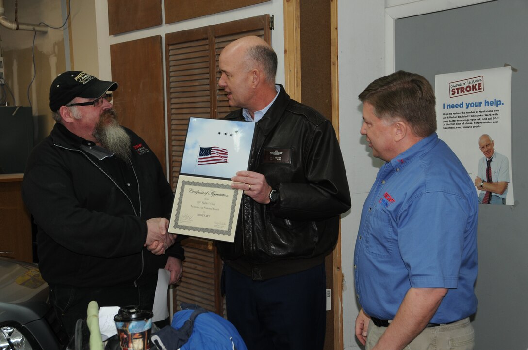 Steve and Mike Howard recieve a thank you certificates from Col. Peter Hronek for all the work they did in restoring a 2001 Honda CRV for the Recycled Rides.  (U.S. Air Force photos by Senior Master Sgt. Eric Peterson)