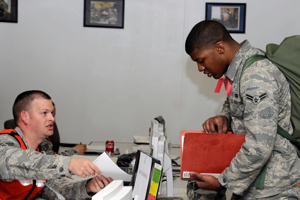 U.S. Air Force Staff Sgt. Richard Blake, left, 35th Aerospace Medicine Squadron public health, processes Airman 1st Class Armanni Thompson, 35th Aircraft Maintenance Squadron, through the personnel deployment function line portion of an operational readiness exercise at Misawa Air Base, Japan, April 27, 2012. The PDF is the final check ensuring all deploying airmen’s paperwork and medical records are complete and up-to-date before leaving. (U.S. Air Force photo by Tech. Sgt. Marie Brown/Released)