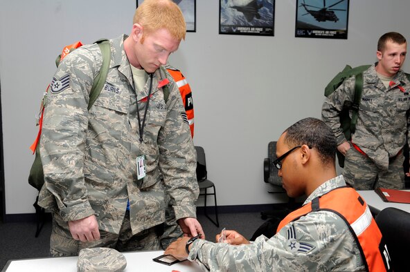 U.S. Air Force Senior Airman Deshun Scott, right, 35th Force Support Squadron, checks identification on Staff Sgt. Ross Burns, left, 35th Aircraft Maintenance Squadron, as he processes through the personnel deployment function line portion of an operational readiness exercise at Misawa Air Base, Japan, April 27, 2012. The 35th Fighter Wing is currently going through an operational readiness exercise to test their ability to deploy personnel, equipment and support assets to a combat environment. (U.S. Air Force photo by Tech. Sgt. Marie Brown/Released)