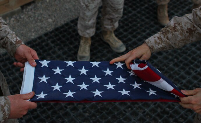 Sergeants Nicholas J. Coban, a native of Pittsburgh, and Bryce W. Cherryholmsnoll, a native of Huxley, Iowa, both U.S. Marines serving with Task Force Leatherneck, 1st Marine Division (Forward), fold the American flag that was flying over the Task Force Leatherneck compound here April 27, 2012. Marines serving here have the opportunity to fly a 3-by-5-foot American flag for a day and dedicate it to someone of their choice.
