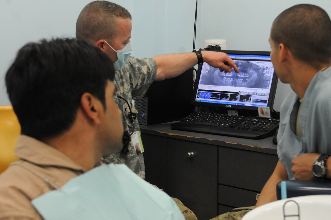 U.S. Army Capt Robert Rehl, general dentist, and Private 1st Class Elisamuel Suarez, dental technician, 502nd Dental Company, Area Support, 1st Medical Brigade, explain to Afghan air force Sgt. Mohammad Noori, an Afghan Mi-17 Helicopter flight engineer, the findings of his X-ray at the Role 3 Hospital at Kandahar Air Wing, Afghanistan, April 19, 2012. Noori was taken to seek medical attention by advisers from the 738th Air Expeditionary Advisory Group, after he complained of tooth pain during his annual flight physical. (U.S. Air Force photo by Staff Sgt. Nadine Y. Barclay)