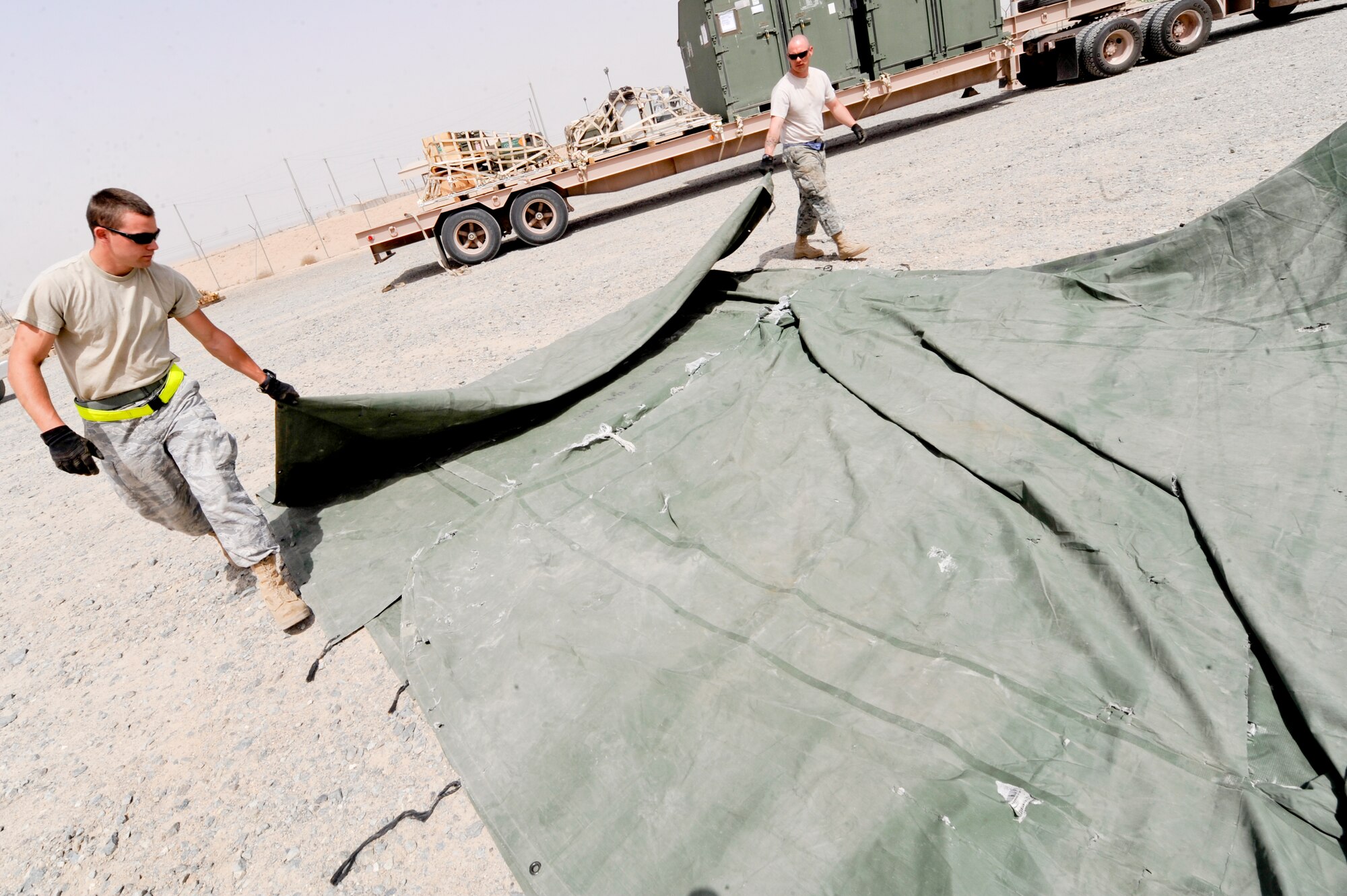 SOUTHWEST ASIA -- Senior Airman Zachary Crutchman (Left), and Tech. Sergeant Christopher Loar, 332nd Expeditionary Logistics Readiness Squadron members, fold a tarp after downloading cargo here, April 26, 2012. Tarps are used to shield pieces of equipment from the elements during transport. Crutchman is deployed from Nellis Air Force Base, Nev., and is a native of West Virginia. Loar is deployed from Little Rock Air Force Base, Ark., and is a native of Blissfield, Mi. (U.S. Air Force photo by Staff Sgt. Joshua J. Garcia)