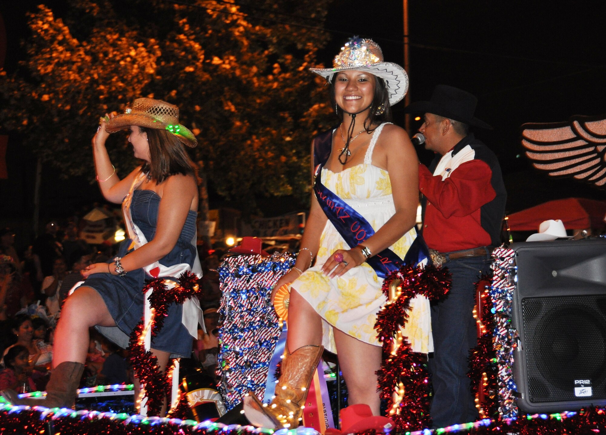 Spectators yell "Show me your shoes" a Fiesta tradition, to see the footwear that the float riders are wearing. Airman Klorissa Ramirez, 433rd Force Support Squadron, obliges and shows off her illuminated boots, as Senior Airman Cassandra Toole, 433rd Force Support Squadron waves to the crowd during the Flambeau Parade, April 28, 2012. 