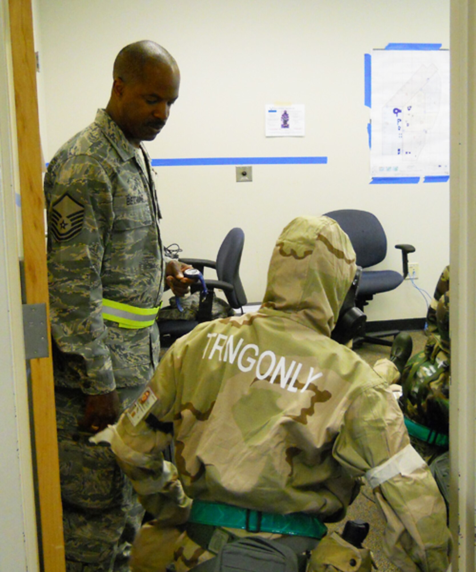 Master Sgt. Richard Bethune, Headquarters 22nd Air Force cyber systems operator and Exercise Evaluation Team member, evaluates an Airman’s ability to perform while wearing a Joint Service Lightweight Integrated Suit and protective mask during a simulated chemical attack, April 26, at Gulfport Combat Readiness Training Center, Miss. Members of 22 AF assisted the 514th Air Mobility Wing, Joint Base McGuire-Dix-Lakehurst and the 974th Airlift Wing, Minneapolis-St. Paul Air Reserve Station, Minn., during a Readiness Assistance Visit in preparation for their upcoming Air Mobility Command Operation Readiness Inspection. (U.S. Air Force photo/Master Sgt. James Branch)