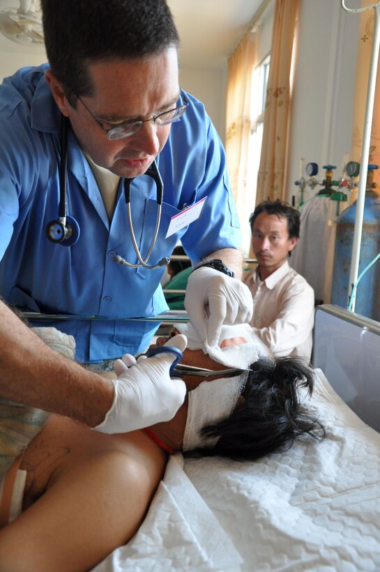 U.S. Air Force Lt. Col. David Worley, a critical care transport nurse, removes the dressing from Neng Yong Ya's head, April 27, at the Lao-Mongolian Friendship Hospital in Phonsavahn, Xieng Khouang Province, Laos. Mr. Ya, a 30-year old farmer, was critically injured April 24 when a Vietnam-era unexploded ordnance blew up as he attempted to remove a stump from a field. Worley is working with Operation PACIFIC ANGEL 12-2, a joint and combined humanitarian mission, and is normally assigned to the 123rd Medical Group of the Kentucky Air National Guard. (U.S. Air Force photo/Master Sgt. Mike Hammond/Released)