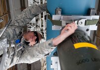 Senior Airman Brian Arbogast, 28th Aircraft Maintenance Squadron weapons load-crew member, installs a bomb strap on a BD-52 bomb while unloading it from a B-1 on the flightline at Ellsworth Air Force Base, S.D., April 26, 2012. Strapping down the bomb ensures that it stays secure during the process. (U.S. Air Force photo by Airman 1st Class Kate Thornton/Released)