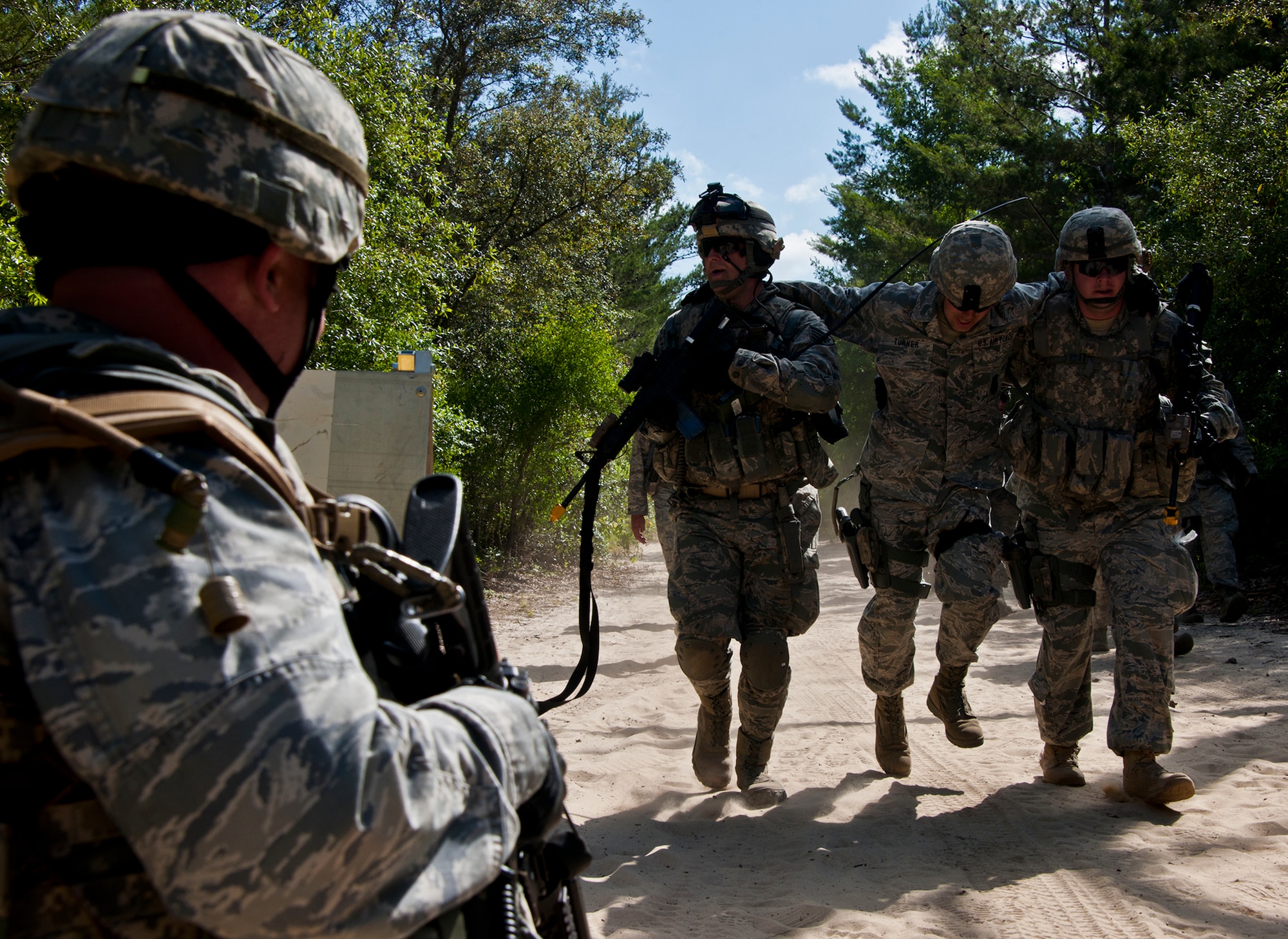 (Left) Lt. Col. Scott Foley, the 633rd Security Forces Squadron commander, covers his squad’s return to camp after a simulated firefight during the three-day Brave Defender field training exercise April 27.  The exercise is the culmination of Air Force Materiel Command’s six-week security forces deployment training, administered by the 96th Ground Combat Training Squadron. GCTS instructors teach 10 training classes a year, which consists of improvised explosive device detection and reaction, operating in an urban environment, mission planning, land navigation, casualty care and more. Foley, the former commander of the 96th Security Forces Squadron was just one of more than 100 active-duty and National Guard Airmen attended this training.  (U.S. Air Force photo/Samuel King Jr.)