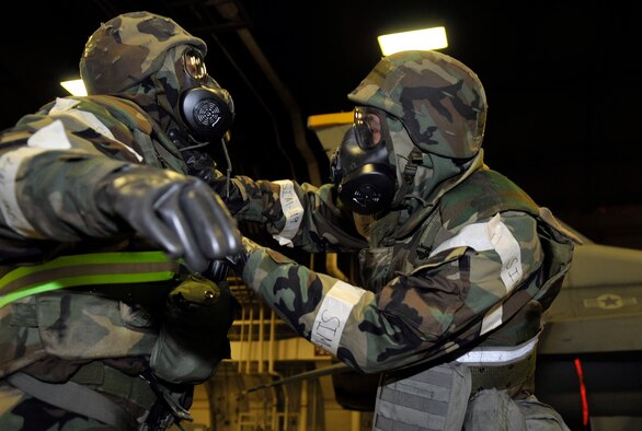 U.S. Air Force Senior Airman Christopher Barnes, left, raises his arms so Airman 1st Class Tyler Mosholder can perform a buddy inspection of Barnes' gas mask and hood during an operational readiness exercise May 01, 2012 at Misawa Air Base, Japan. Barnes and Mosholder are 35th Maintenance Squadron fuel systems technicians. OREs help Misawa's Airmen stay prepared and ready to fight in a deployed environment. (U.S. Air Force photo by Tech. Sgt. Phillip Butterfield/Released)