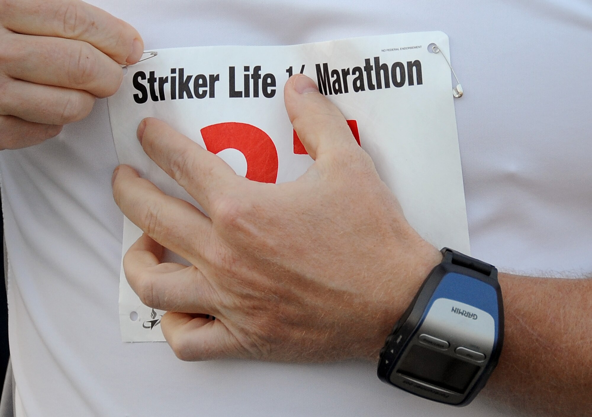 A marathon participant pins his bib number to his shirt prior to the Air Force Global Strike Command Striker Life Half Marathon on Barksdale Air Force Base, La., April 28. Bib numbers are used for race directors to tell runners apart and simplify the task of getting a time for each of the 150 runners who participated in the event. (U.S. Air Force photo/Staff Sgt. Amber Ashcraft)(RELEASED)