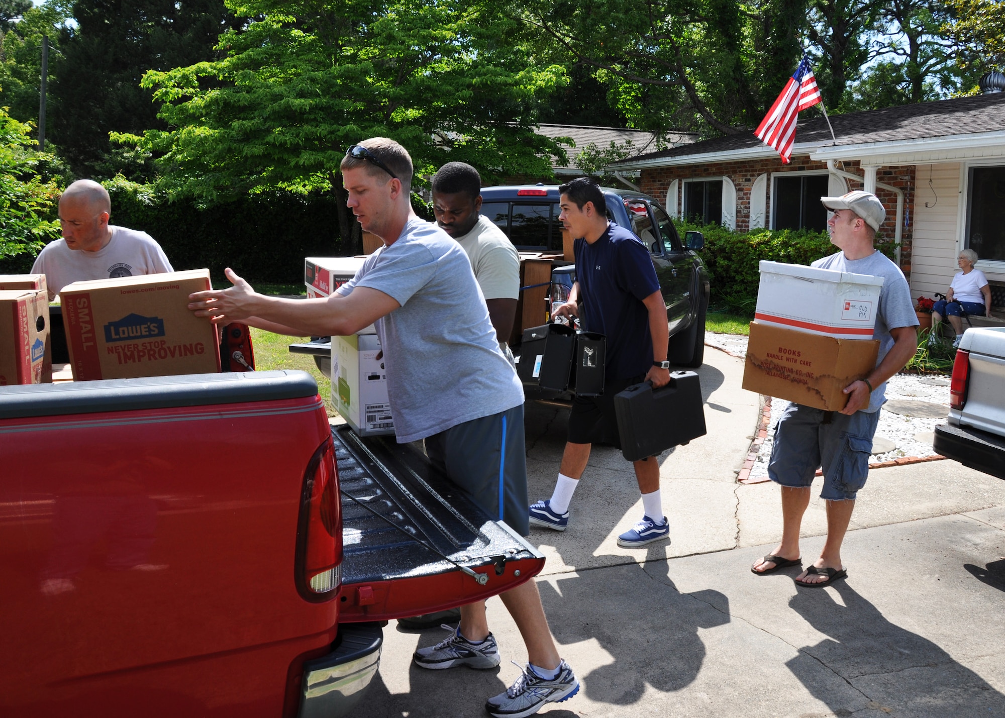 Airmen from Eglin Air Force Base and Duke Field move boxes of household items onto awaiting pickup trucks outside the home of Lucy Harstvedt (seated, far right) in Shalimar, Fla., April 20, 2012.  Eight Airmen responded to a call for volunteers to help Harstvedt, an Air Force widow since 1964, relocate to the nearby Bob Hope Village since she was unable to conduct the move. Bob Hope Village, a retirement home for surviving spouses of Air Force enlisted members, is part of the overall non-profit Air Force Enlisted Village. (U.S. Air Force photo/Dan Neely)