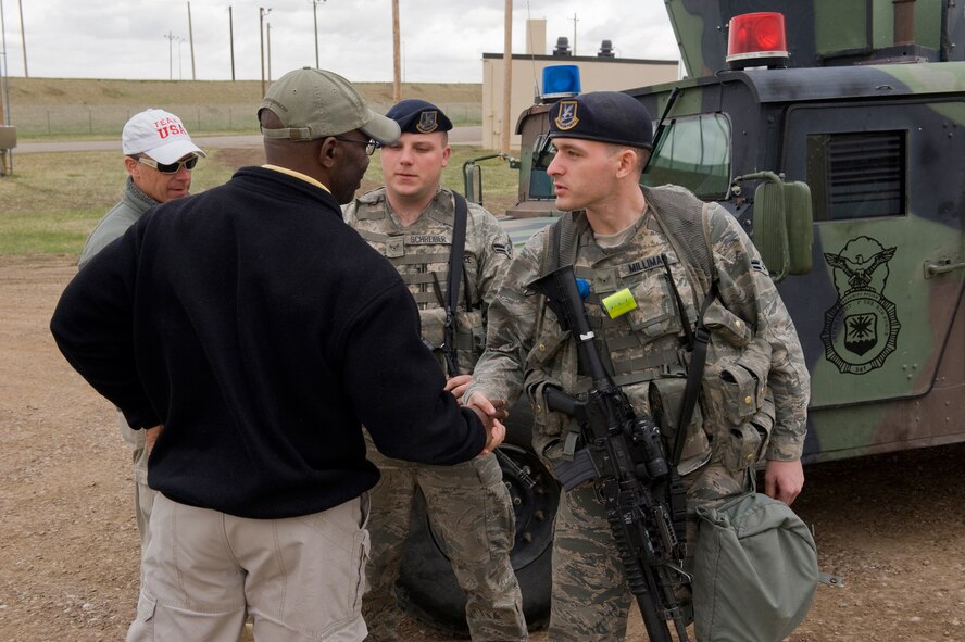 Retired Army Master Sgt. Howard "Mad Max" Mullen, past U.S. Army Ranger, coins Airman 1st Class Daniel Milliman, 341st Security Forces Squadron member, during his tour of the base April 18. Airman 1st Class Seth Schrieber, 341st Security Forces Squadron member looks on. Mullen's embed with the various security forces specialties was part of the ongoing resiliency tours sponsored by Air Force Global Strike Command through the American300 organization. (U.S. Air Force photo/Beau Wade)