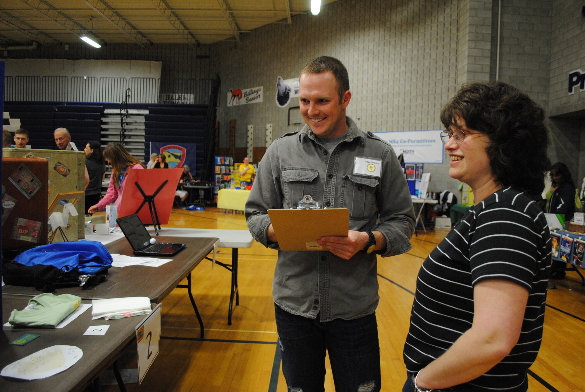 Airman 1st Class Travis Evans, 341st Civil Engineer Squadron draftsman, judges 11-year-old Max Weissman's booth titled "Types of Gears," while Max's mom, Wendy, looks on. Malmstrom Airmen volunteered to judge more than 200 presentations done by children ages 5 to 18. (U.S. Air Force photo/Airman 1st Class Katrina Heikkinen)