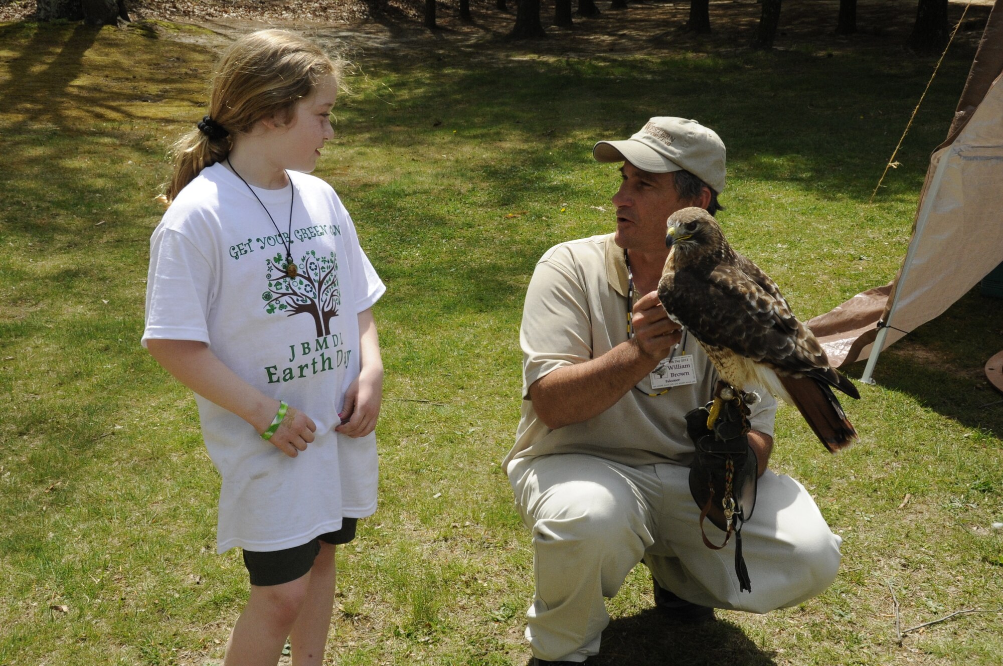 Jessica, 9, learns about the flying and hunting abilities of falcons from William Brown, a falconer with the New Jersey Falconry Club, during the Joint Base McGuire-Dix-Lakehurst Earth Day event April 21 at the Laurel Pond Recreation Area. Jessica is the daughter of Cindy Cristantiello, an assistant of the Earth Day Lizard Guys reptile exhibit. The falconers also released a red-tailed hawk back into the wild during the festivities because it had completed its career in falconry. (U.S. Air Force photo by Senior Airman Bryan Swink/Released)