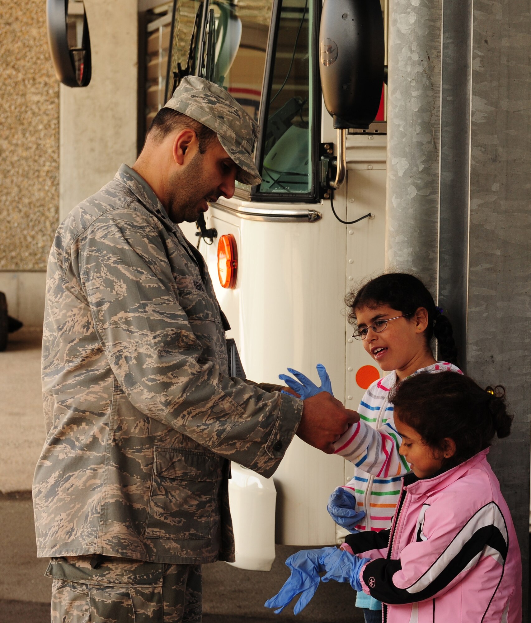Capt. Walid Habash, Chaplain, helps his daughters  put on gloves before a simulated litter carry at the 86th Aerospace Medical Squadron on Ramstein Air Base, Germany, April 27, 2012. Job Shadow Day in the Kaiserslautern Military Community is an annual event in which children have the opportunity to shadow their sponsor or a work place mentor, completing a half-day on the job in an effort to introduce the young people the working community through participation. (U.S. Air Force photo/ Airman 1st class Kendra Alba)