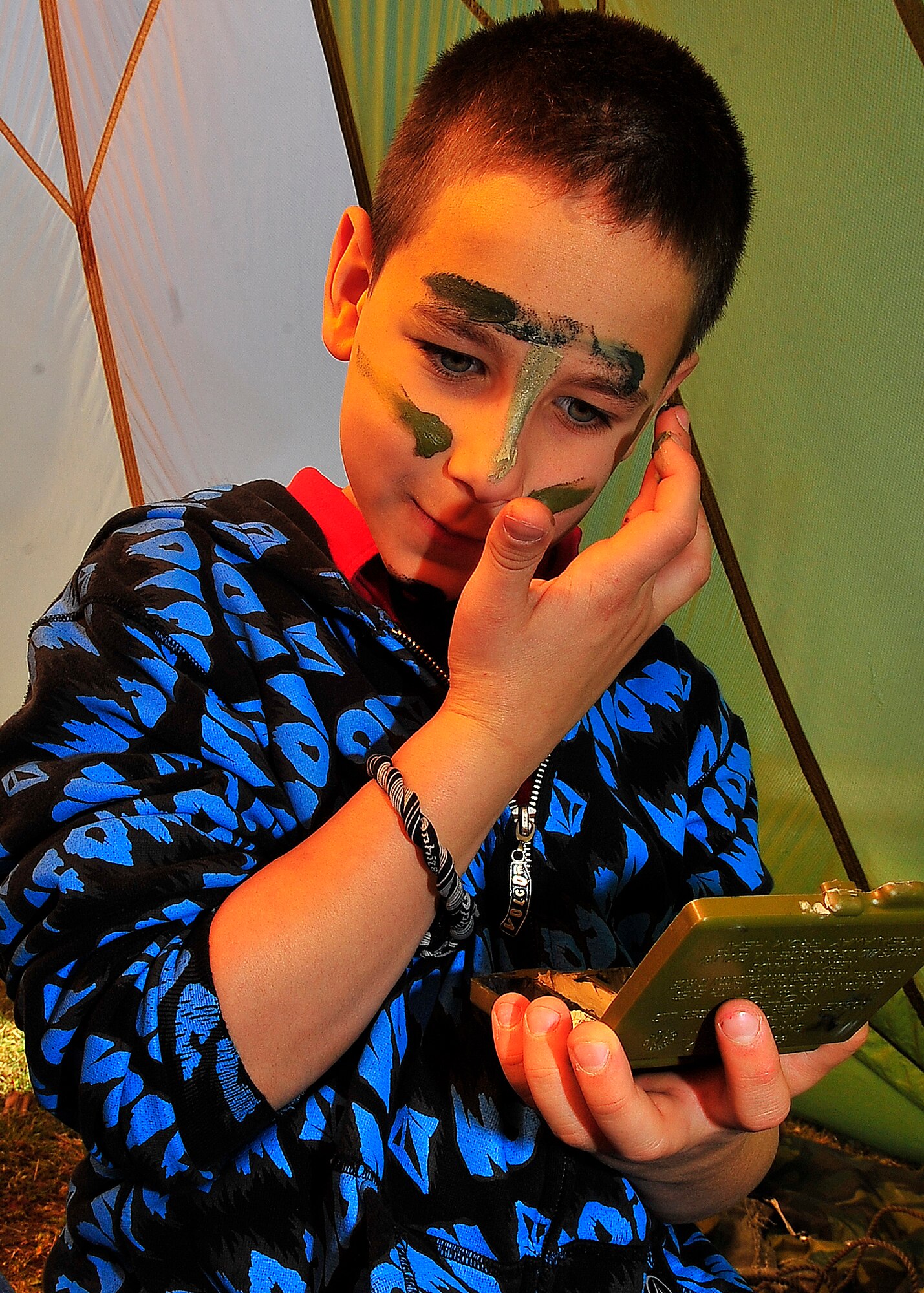 Students from Ramstein Intermediate and Middle schools participated in the Kaiserslautern Military Community Job Shadow Day event on Ramstein Air Base, Germany, April 27, 2012.  A student from Ramstein Intermediate School applies face camouflage in the survival shelter sponsored by the 86th Operations Support Squadron.  (U.S. Air Force Photo/Staff Sgt. Daylena Gonzalez)