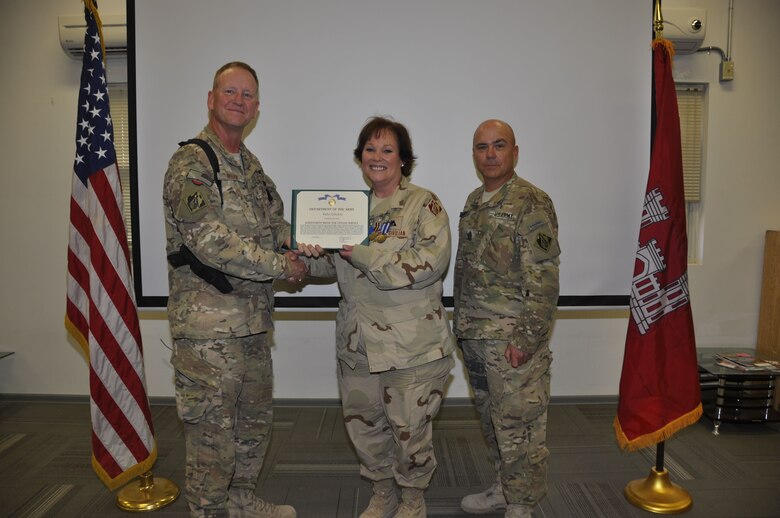 KANDAHAR AIRFIELD, Afghanistan — Col. Benjamin Wham, U.S. Army Corps of Engineers Afghanistan Engineer District-South commander (left), and Command Sgt. Maj. Lorne Quebodeaux (right), present Kelly Gilhooly with the Achievement Medal for Civilian Service Apr. 21. Gilhooly deployed to the South District from Rock Island, Ill. to serve as the process improvement manager.