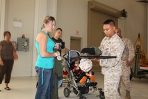 Sgt. John Garganera presents the Rapini family with gifts from Marine Corps Air Station New River as part of Cole Rapini's visit. The Family has traveled across the country trying to accomplish all of the tasks put onto 'Cole's Bucket List', a list of activities for Cole and his family to do together. The family received various tokens including a child's flight suit for Cole, a custom paddle laser engraved to commemorate the visit, and a poster with Coles name on it, July 24.
