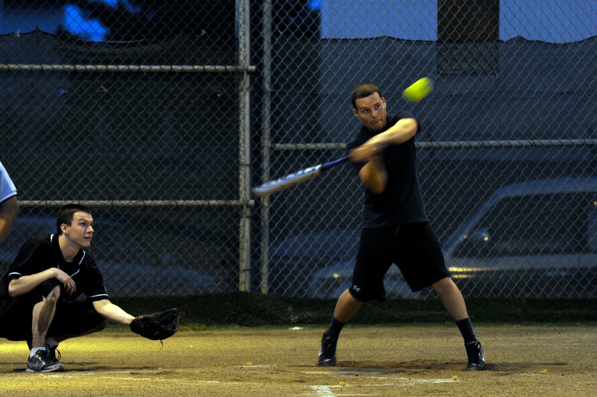 U.S. Air Force Airman Kyle Hawkins, 35th Force Support Squadron, prepares to catch the ball as U.S. Navy Mass Communication Specialist 2nd Class Pedro Rodriguez, Commander Task Force 72, swings at the ball during the base intramural softball championship game at Misawa Air Base, Japan, Aug. 1, 2012. At the end of seven innings CTF-72 captured the championship title 14-13 against 35 FSS. (U.S. Air Force photo by Tech. Sgt. Marie Brown)