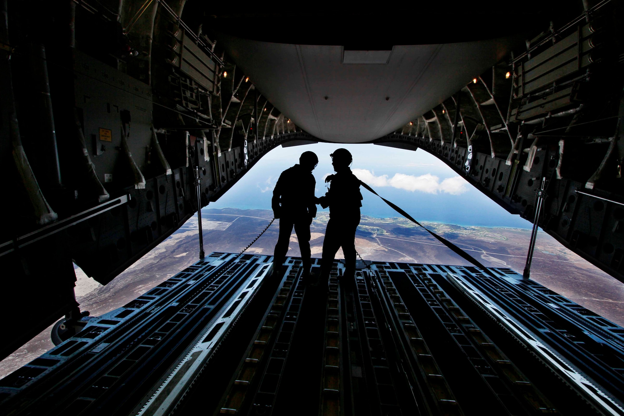 (From right) Master Sgt. Brian Chewning, 15th Operations Group C-17A Evaluator Loadmaster, talks with Jimmie Spillers, 535th Airlift Squadron loadmaster, during a local sortie July 31 at Joint Base Pearl Harbor-Hickam, Hawaii. During the flight, the aircrew dropped a container delivery system bundle as well as a heavy extraction platform to simulate dropping pallets of supplies to forward-deployed troops in austere locations. (Photo by Dennis Oda)