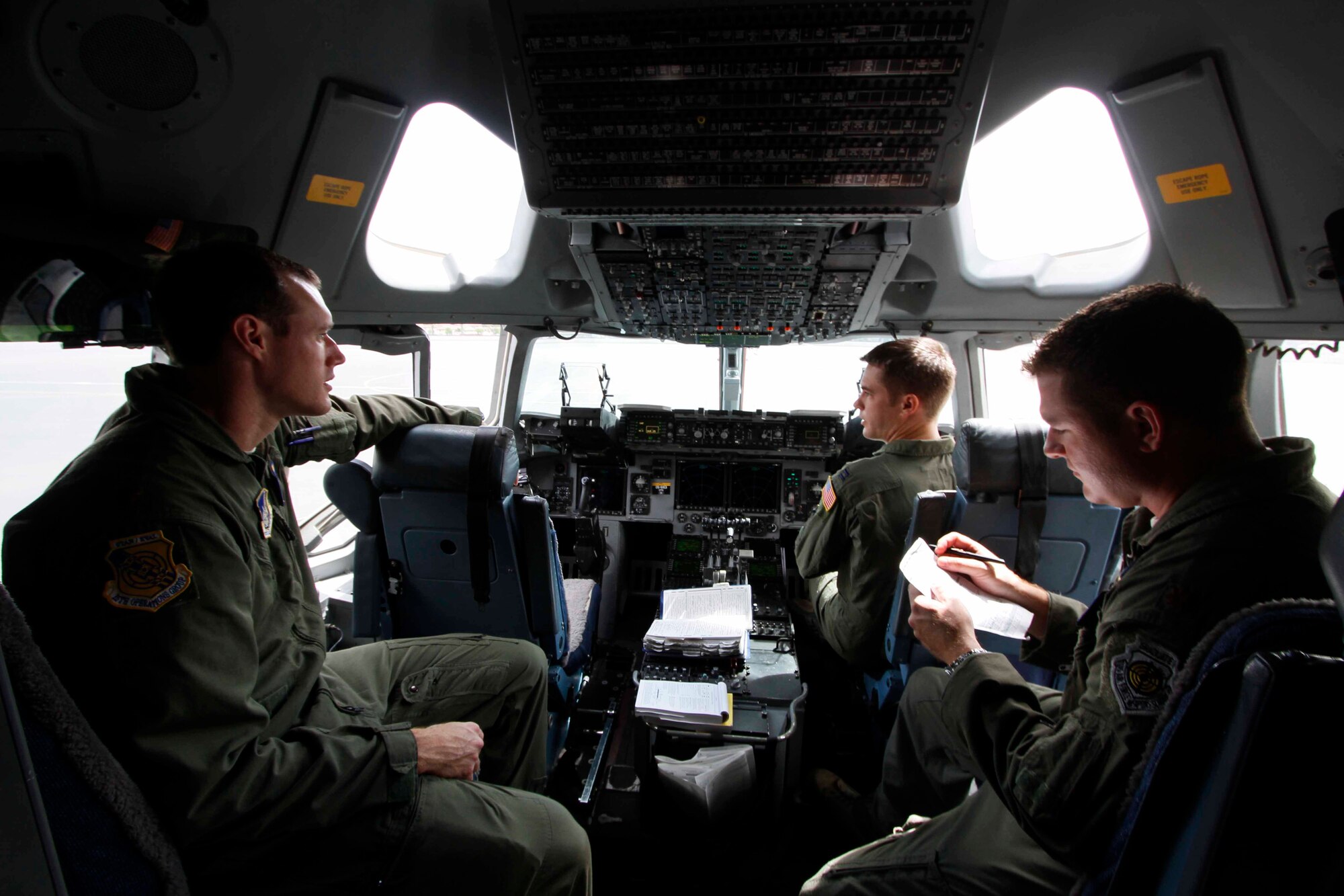 (From left) Maj.Jon Baize, Capt. Mike Recker, and Maj. Alan Partridge, C-17 Globemaster III pilots, discuss pre-flight checklist requirements July 31 at Joint Base Pearl Harbor-Hickam, Hawaii. During the flight, the aircrew dropped a container delivery system bundle as well as a heavy extraction platform to simulate dropping pallets of supplies to forward-deployed troops in austere locations. (Photo by Dennis Oda)