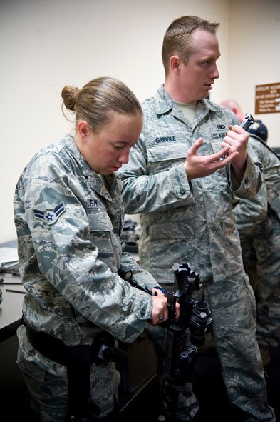 Airman 1st Class Ellen Smith and Senior Airman Nicholas Gribble, 2nd Security Forces Squadron, clean their weapons in the 2 SFS guard mount room on Barksdale Air Force Base, La., July 31. Personnel must clean their weapons every two weeks, even if they have not been fired, to ensure they are in optimal working condition. (U.S. Air Force photo/Staff Sgt. Chad Warren)(RELEASED)