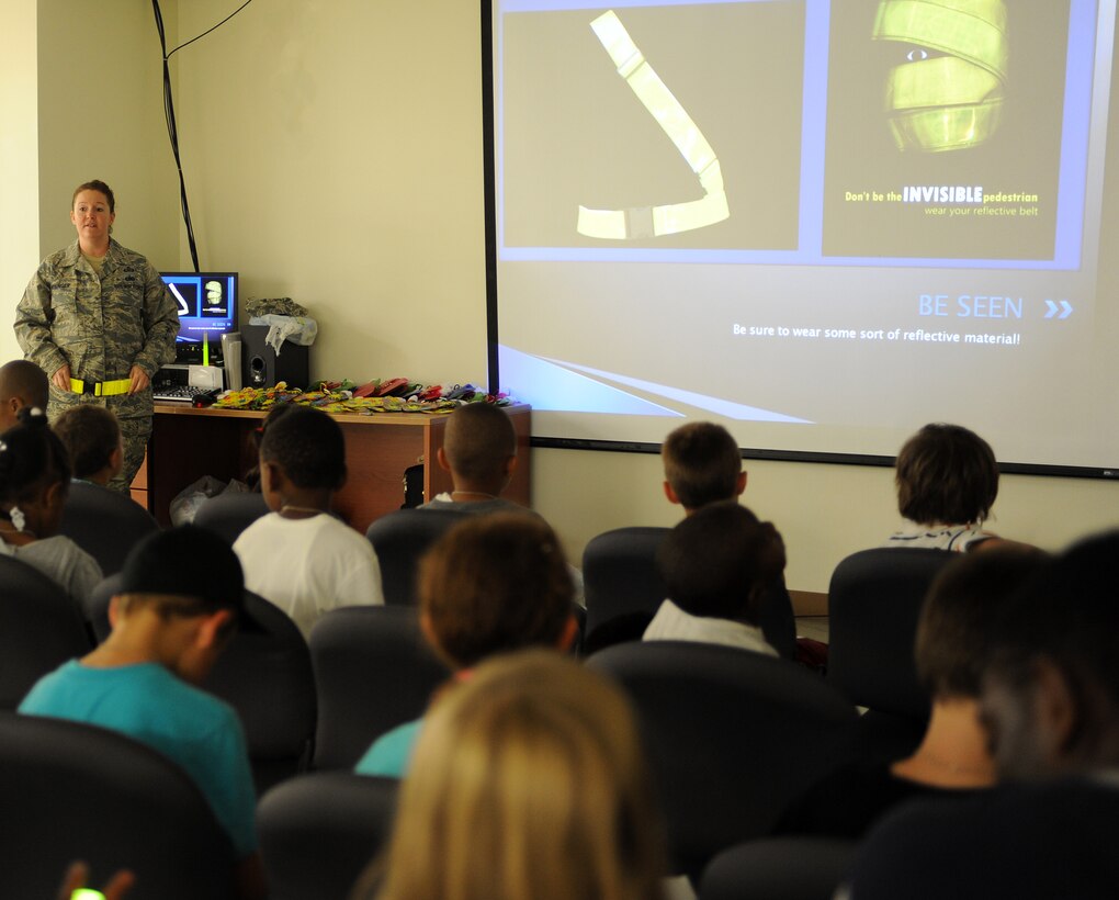 U.S. Air Force Master Sgt. Dawn Moninger, 633rd Air Base Wing Safety noncommissioned officer in charge of ground safety, demonstrates the proper way to wear a reflective belt during Operation Hero, at Langley Air Force Base, Va., Aug. 1, 2012. Operation Hero helps children understand the pre-deployment process by providing entertainment and hands-on activities, allowing children the opportunity to experience what their parents do prior to deploying. (U.S. Air Force photo by Airman 1st Class Teresa Cleveland/Released)