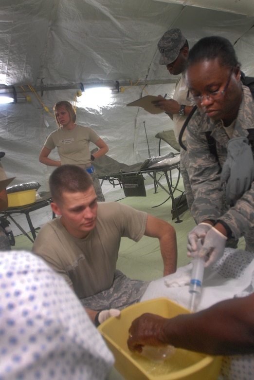Medical Technicians Tech. Sgt. Robin Woodey and Senior Airman Jacob Watters iirrigate the wound of a roleplayer to try to attemp to remove radioactive particles from the patients arm. (DoD photo by Army Sgt. 1st Class Raymond Piper)