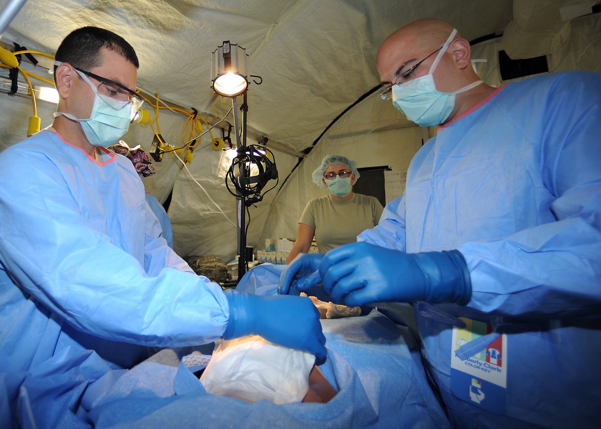 Air Force medical personnel assigned to Expeditionary Medical Support clean an abdominal wound on a simulated injured patient in support of exercise Vibrant Response 13 at Contingency Operating Location Nighthawk at Camp Atterbury, Ind., July 30, 2012. Vibrant Response is a U.S. Northern Command-sponsored field training exercise for chemical, biological, radiological, nuclear and high-yield explosive consequence management forces designed to improve their ability to respond to catastrophic incidents. (U.S. Air Force photo by Tech. Sgt. Tony Tolley)