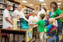 Volunteers, Regan Person and Lexy Klinger hand out gift bags to participants of the summer reading program July 28, at Joint Base San Antonio- Randolph, Texas. (U.S. Air Force photo by Benjamin Faske)