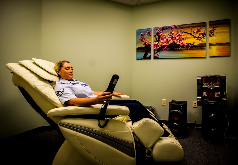 Staff Sgt. Amanda Hastings, Health and Wellness Center office manager and 628th Medical Group medical technician, demonstrates the massage chair in the relaxation room at the HAWC, July 31 at Joint Base Charleston – Air Base, S.C. The relaxation room consists of mood lighting, relaxing music and a massage chair that Airmen can take a few minutes to relax and reflect on their day as long as the HAWC is open. The HAWC’s mission is to cultivate a fit and healthy force. (U.S. Air Force photo by Senior Airman Dennis Sloan/Released)