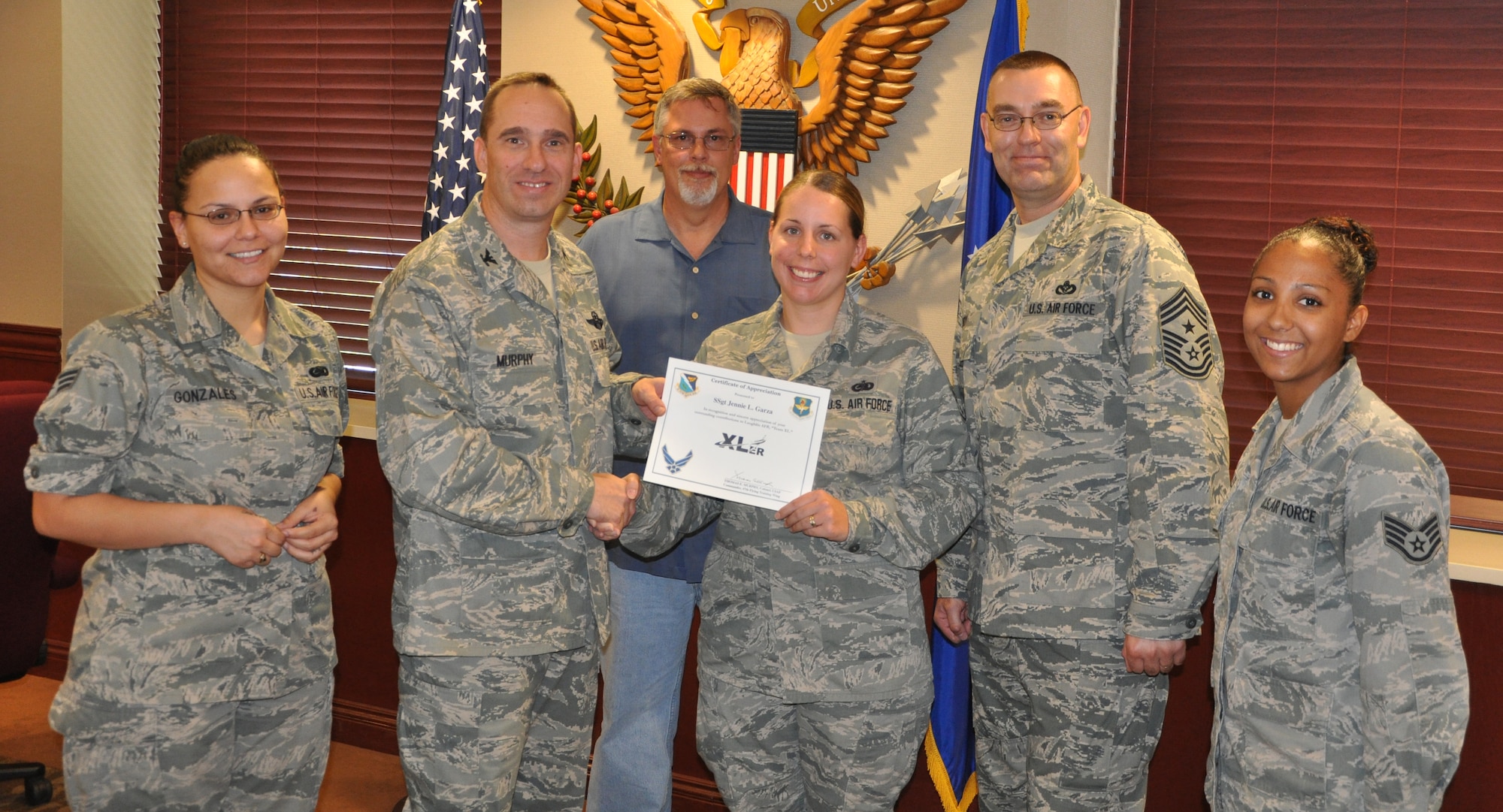 Staff Sgt. Jennie Garza, 47th Mission Support Group NCO in charge of logistic plans, poses with Col. Tom Murphy, 47th Flying Training Wing commander, and Chief Master Sgt. Garry Berry, 47th FTW command chief, after being presented the XLer of the week award at Laughlin Air Force Base, Texas, July 24, 2012. The XLer is a weekly award chosen by wing leadership and given to those who consistently make outstanding contributions to Laughlin and their unit. (U.S. Air Force photo/Joel Langton)