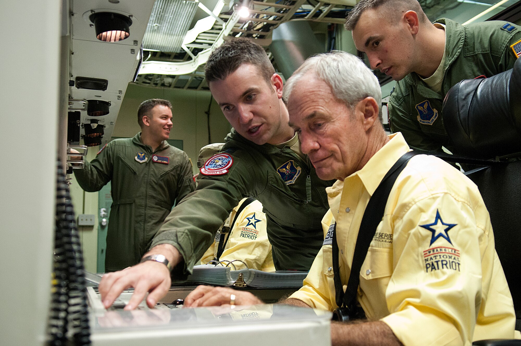 Capt. Joseph Zito, 319th Missile Squadron, shows retired Marine Col. John Bates, three-time Purple Heart recipient, the workings of the console of a launch control center during a tour of the missile procedures trainer on F.E. Warren AFB, Wyo., Thursday, July 26, 2012. Bates visited the F.E. Warren Airmen, as part of the American300 Behind the Chutes tour. Capt. Derrick Besse, 320th Missile Squadron, looks over Bates' shoulder. (U.S. Air Force photo by R.J. Oriez)