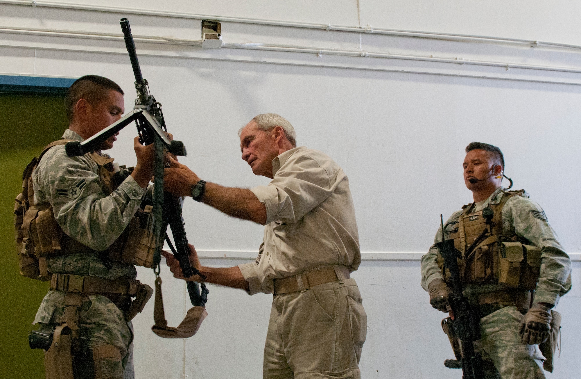Airman 1st Class Mario Soriano, 90th Security Group tactical response force, shows retired Marine Col. John Bates a 240 Bravo machine gun used by the TRF as Staff Sgt. Adrian Norwood looks on. Bates, a three-time Purple Heart recipient, visited with the TRF Airmen Wednesday, July 25, 2012, as part of the American300 Behind the Chutes tour. (U.S. Air Force photo by R.J. Oriez)
