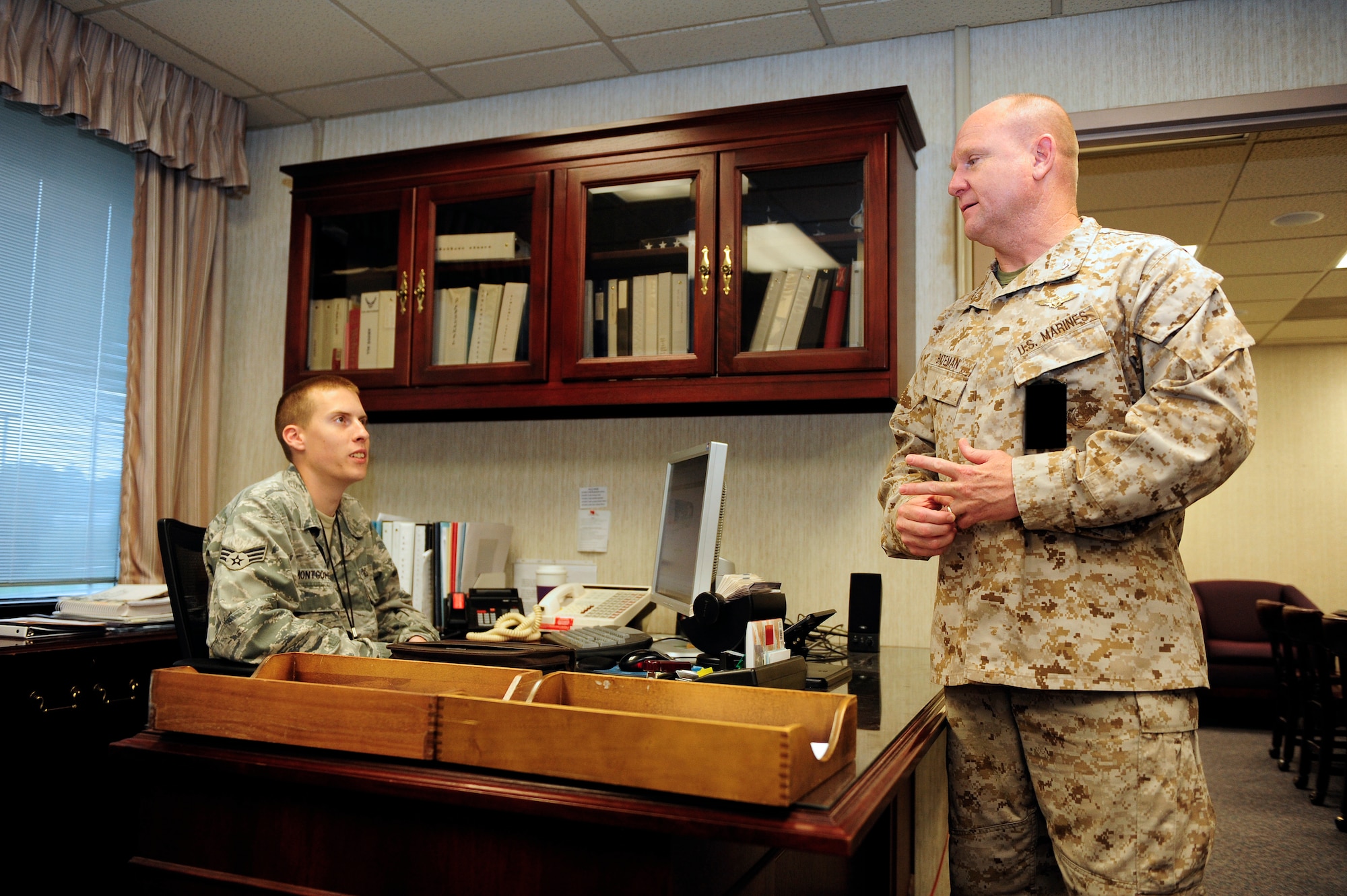 Colonel John Bateman, U.S. Marine Corps Central Command liaison officer to U.S. Air Force Central, talks to Senior Airman Holden Montgomery, AFCENT knowledge operations manager, as the day comes to an end. The MARCENT liaison officer here, he facilitates communications between the two commands.  (U.S. Air Force photo illustration by Airman 1st Class Daniel Blackwell/Released)