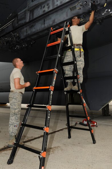 MINOT AIR FORCE BASE, N.D. – Airman  1st  Class Kenneth Williams, 5th Aircraft Maintenance Squadron weapons load crew member, stands as Staff Sgt. Paul Tilghman, 5th AMXS weapons load crew member, prepares a B-52H Stratofortress for armament with simulated weapons here July 16. The aircraft was loaded with test weapons in support of pilot training in regards to “smart weapons” systems. (U.S. Air Force photo/Airman 1st Class Stephanie Ashley)