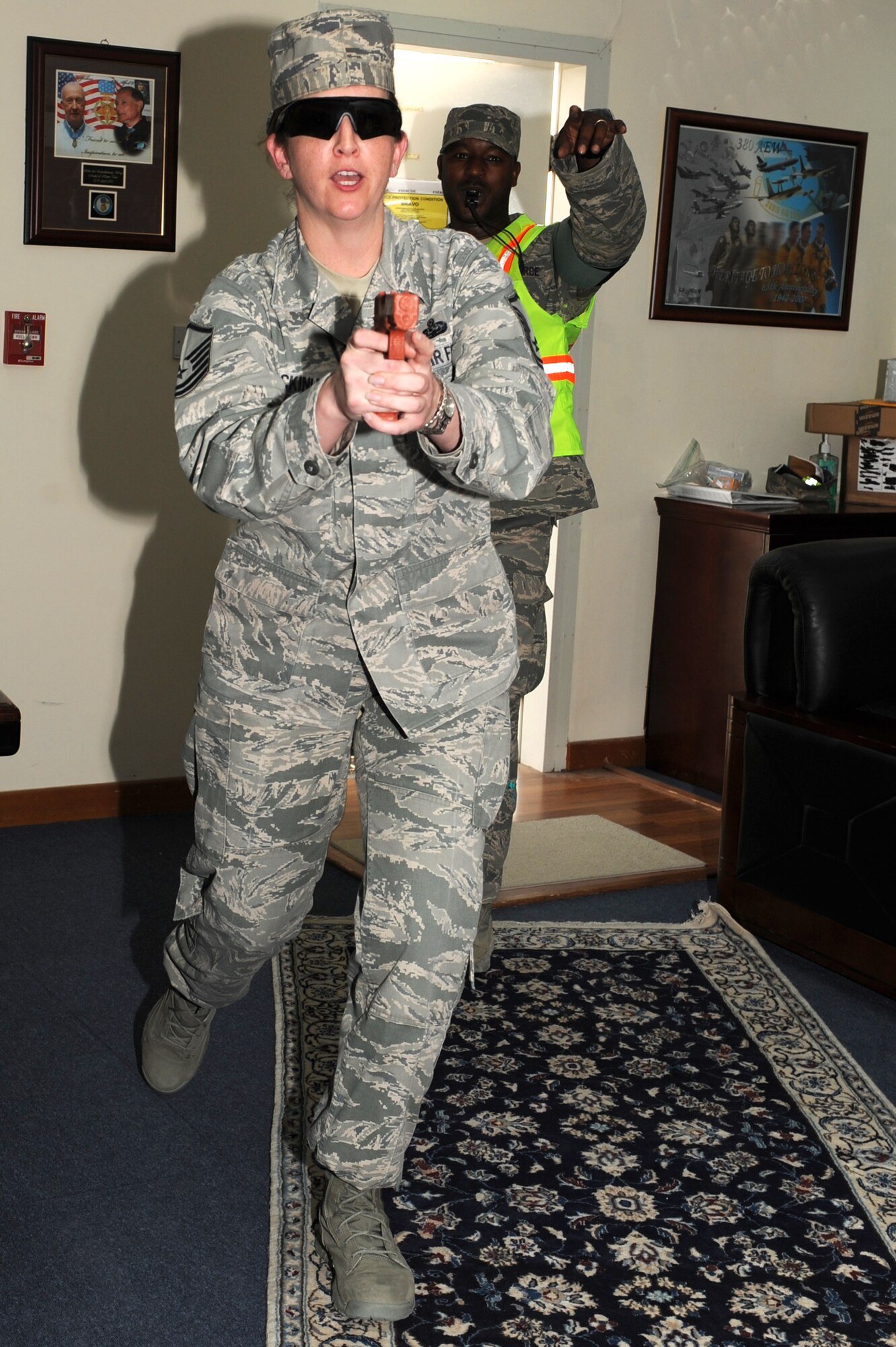 SOUTHWEST ASIA - U.S. Air Force Master Sgt. Jaclyn MacKinley, 380th Air Expeditionary Wing superintendent of wing staff executive services, plays the role of a disgruntled employee with a gun during an active-shooter exercise, as Staff Sgt. Hakim Taylor, 380th Expeditionary Security Forces Squadron Exercise Evaluation Team member, observes the action July 31, 2012. Active-shooter exercises test the base's response to a hostile threat. (U.S. Air Force photo/Master Sgt. Scott MacKay)