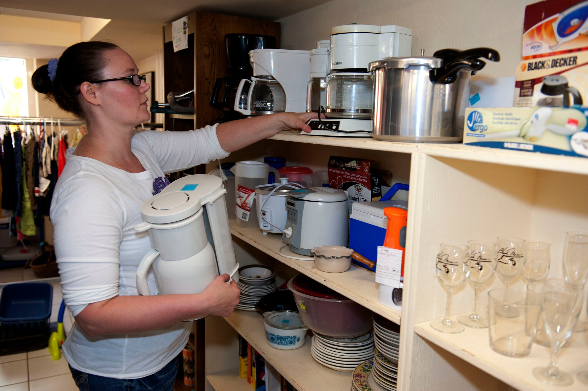 SPANGDAHLEM AIR BASE, Germany – Sara McCoy, Spangdahlem Spouses and Enlisted Member’s Club thrift shop assistant manager, makes room for a donated item on a shelf inside the SSEMC thrift shop here July 31.  All of the profits earned by the thrift shop are returned to the community through the spouse’s club. The shop is open 11 a.m. - 5 p.m. Tuesday through Thursday and the last Saturday of each month. For more information, call DSN 452-2243 or 06565-61-2243. (U.S. Air Force photo by Airman 1st Class Gustavo Castillo/Released)