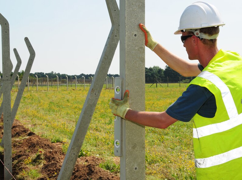 RAF MILDENHALL, England – Paul Watson, a contractor, uses a spirit level to check if a concrete post is straight as he helps put up a security fence around a field next to Taxiway Alpha, RAF Mildenhall. The field is being made into a taxiway extension and will provide extra room which will allow swifter takeoffs for heavier aircraft. Currently, heavy aircraft have to back-taxi to the end of the overrun and turn around, which puts stress on the runway and the undercarriage of the aircraft. Approximately 30 concrete posts, covering a distance of about 700 meters, will be used to make the security fence around the contractors’ compound as they begin construction of the taxiway extension. (U.S. Air Force photo/Karen Abeyasekere)