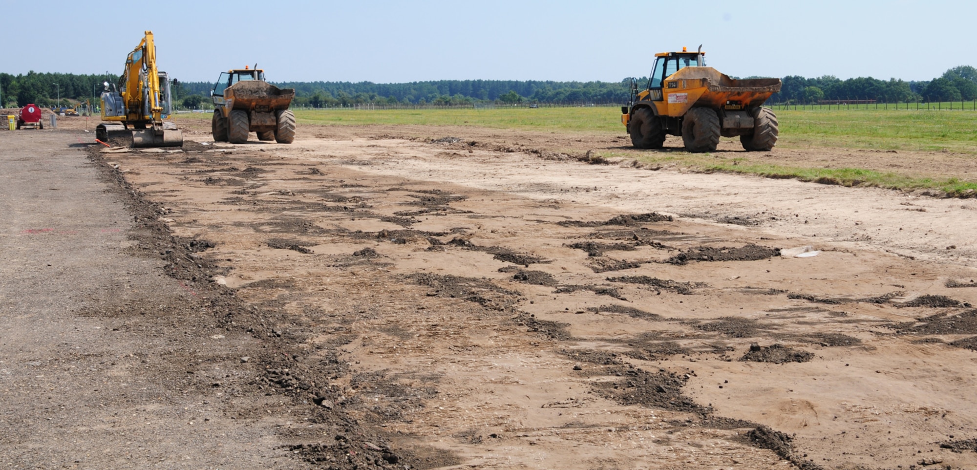 RAF MILDENHALL, England – A 13-ton, 360-degree-tracked excavator removes soil and puts it into two waiting 10-ton dump trucks as they prepare the field area next to Taxiway Alpha, RAF Mildenhall, for construction July 26, 2012. The soil is temporarily stored on site and will be reused in the construction works, which has environmental benefits for the project, the base community and the local community. The contracted design-and-build project will cost approximately $15 million and will benefit RAF Mildenhall by providing direct access for heavily-laden aircraft to launch from the overrun. (U.S. Air Force photo/Karen Abeyasekere)