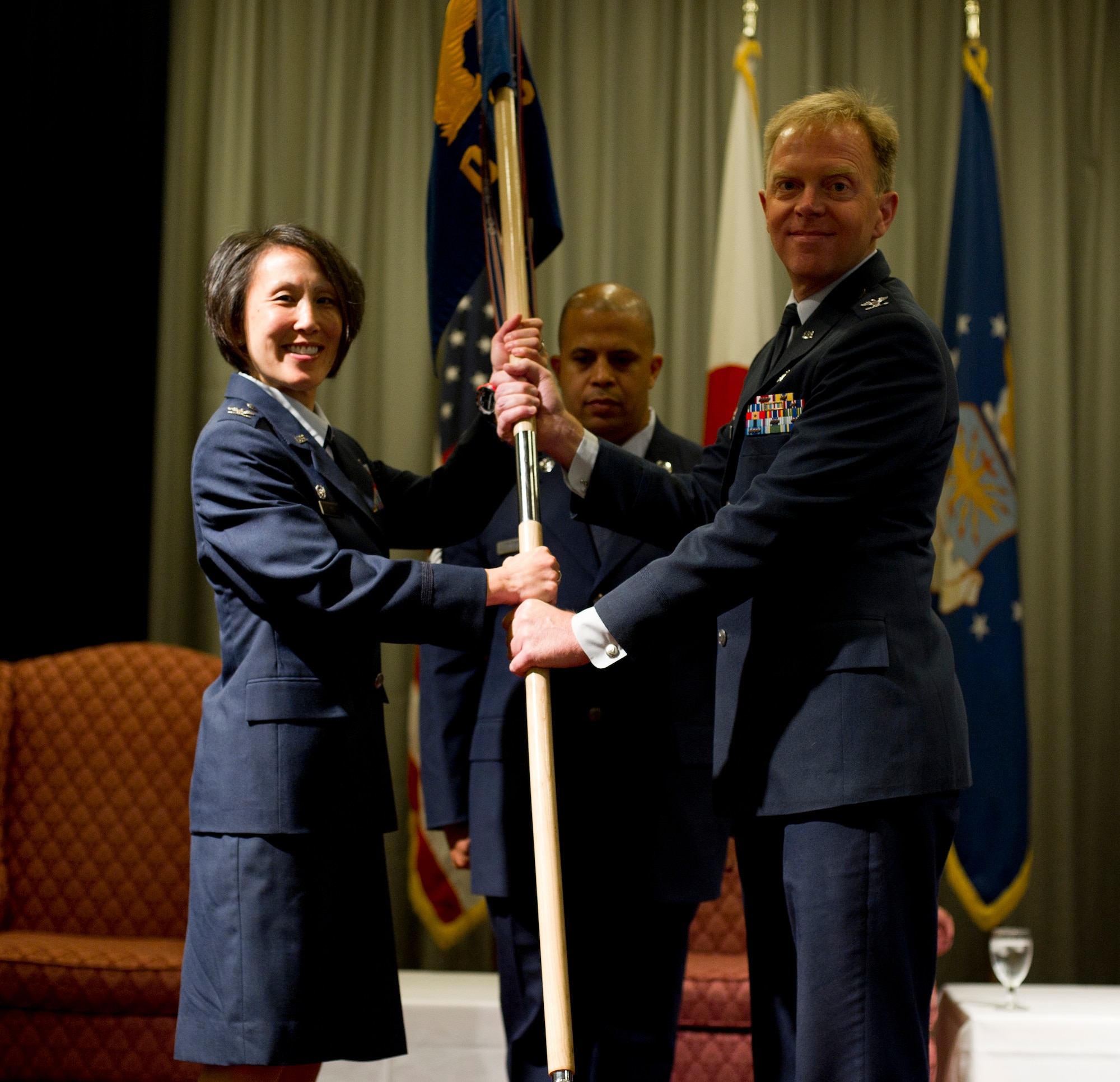 YOKOTA AIR BASE, Japan -- Col. Eveline Yao, commander of the 374th Medical Group, passes the unit guidon to Col. Timothy Claseman during the 374th Dental Squadron change of command at Yokota Air Base, Japan, July 27, 2012. The passing of the guidon symbolizes the passing of responsibility, a tradition dating back to Roman times. (U.S. Air Force photo by Staff Sgt. Stacy Moless)