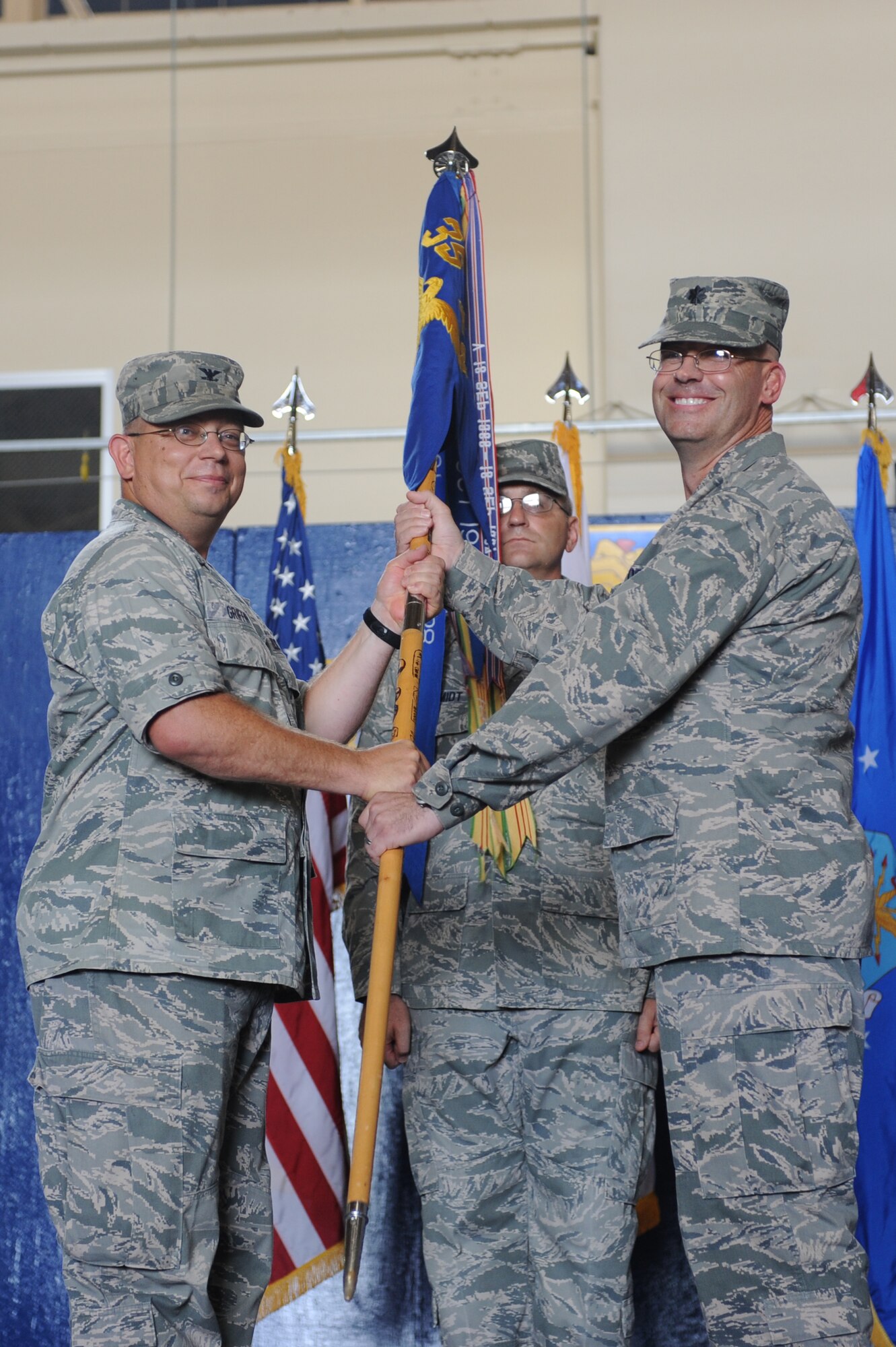 U.S. Air Force Lt. Col. Dwayne Robison, right, passes the guidon to Col. Michael Griffin, 35th Mission Support Group commander, during a change of command ceremony at Misawa Air Base, Japan, Aug. 1, 2012. The guidon symbolizes the relinquishment of command from the outgoing commander to the incoming commander. Robison is relinquishing command of the 35th Civil Engineer Squadron to Lt. Col. Robert Grainger. (U.S. Air Force photo by Airman 1st Class Kia Atkins/Released)