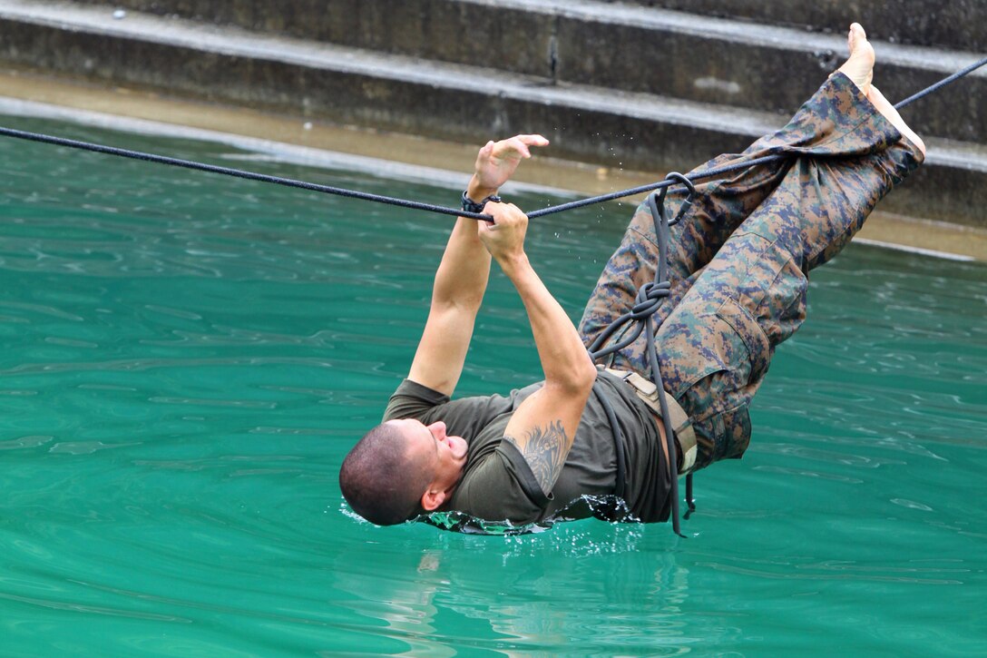 A reconnaissance Marine traverses across the water-crossing lane during reconnaissance training at the Jungle Warfare Training Center at Camp Gonsalves July 25. The purpose of the training was to improve tactics, techniques and procedures for operating in a jungle environment. The Marine is with Force Company.
