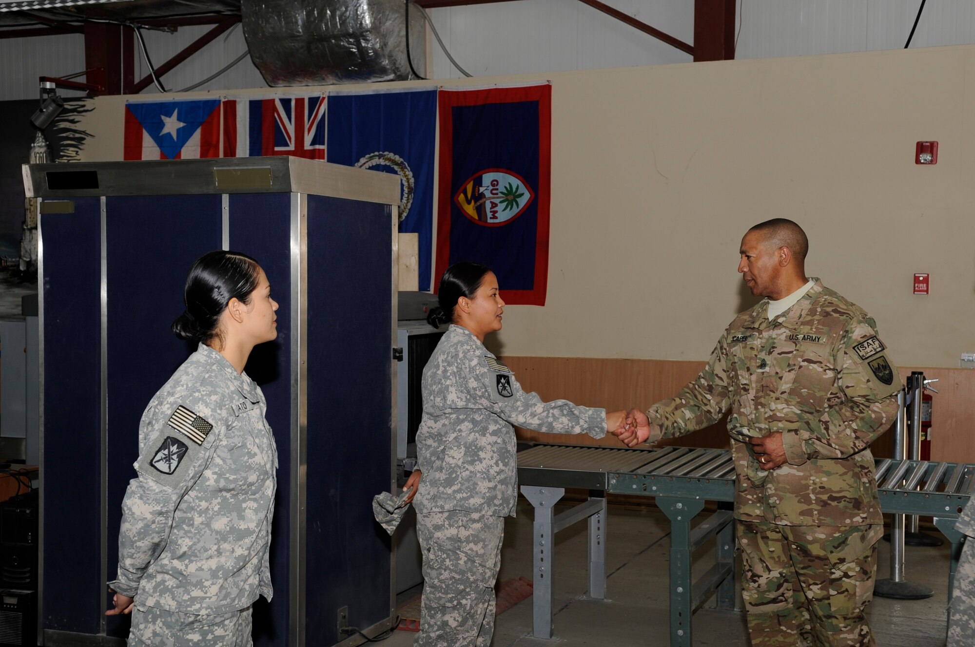 Army Command Sgt. Maj. Thomas Capel, International Security Assistance Force and United States Forces – Afghanistan senior enlisted advisor presents a superior performer coin to Spc. Kellie Mantanona during a tour of the Transit Center at Manas, Kyrgyzstan, Aug. 1, 2012. Mantanona serves as a customs agent at the Transit Center and is assigned to the 368th Military Police Company, Detachment 4. She is currently deployed from the U.S. Army Reserve Center, Barrigada, Guam. (U.S. Air Force photo/Master Sgt. Jason Vaught)