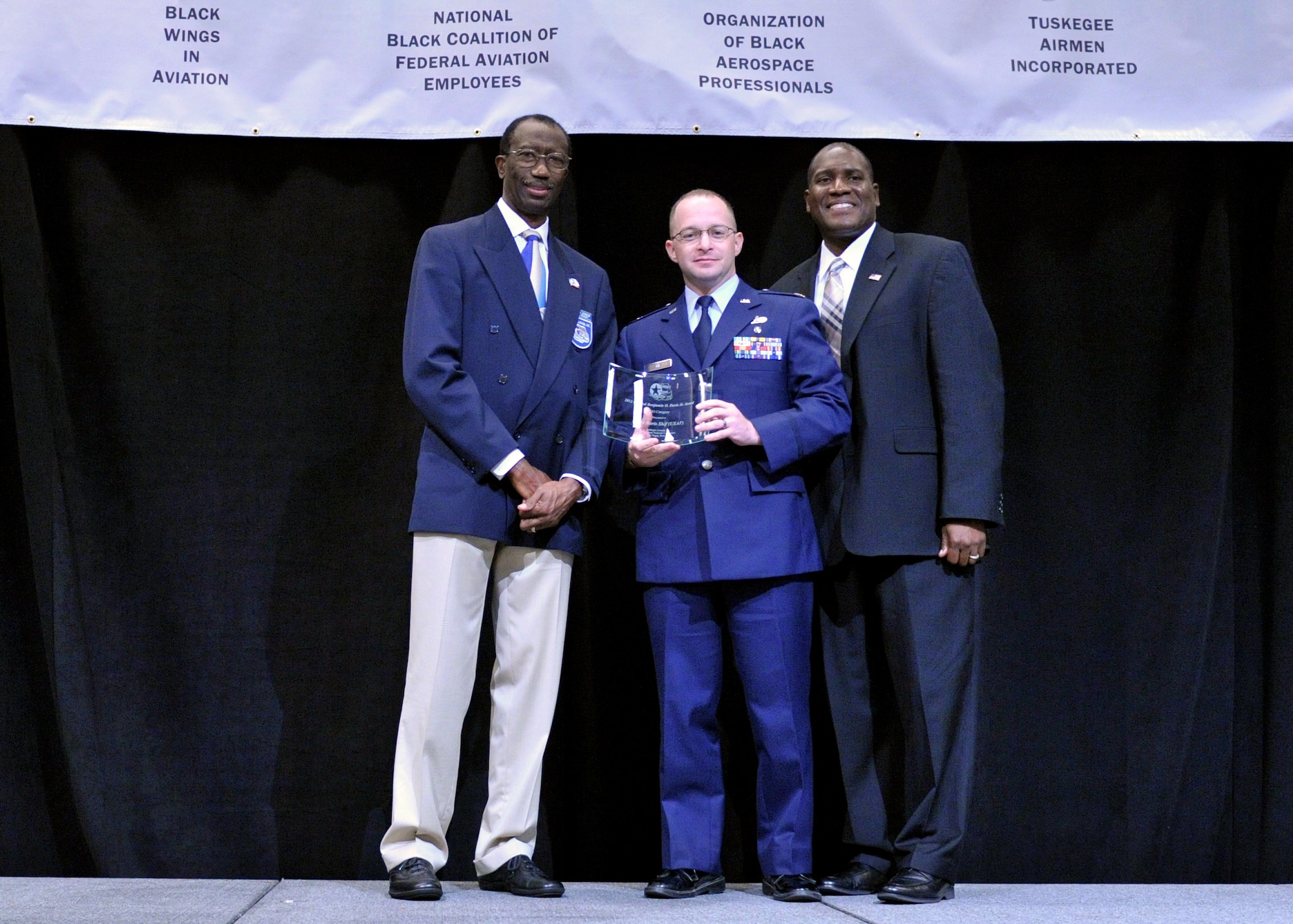 Major Boris Shif, (center) was awarded the General Benjamin O. Davis, Jr. Award.  Shif is the director of operations at the 316th Training Squadron, Goodfellow Air Force Base, Texas. Air Force, Retired Brig. Gen. Leon Johnson presented the award to Shif on behalf of Tuskegee Airmen, Inc. during the Military Luncheon, at the Las Vegas Hotel, Aug.1. (U.S. Air Force photo/A1C Colville McFee)