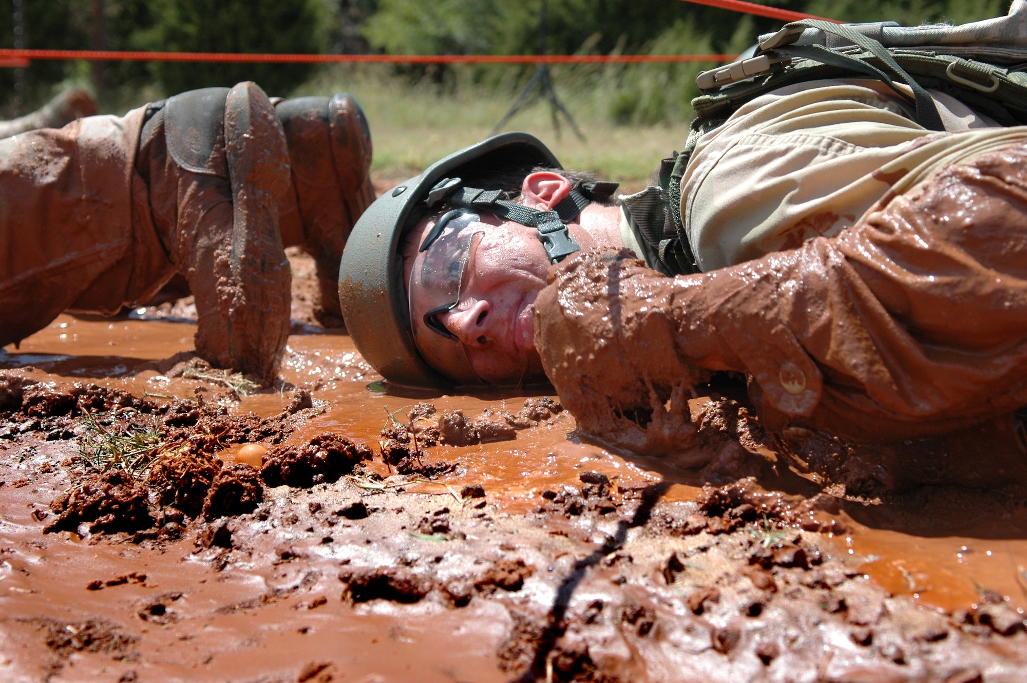 Air Force Academy Cadet 2nd Class Josh Beaker squirms through the mud in a line of fellow classmates at the 3rd CCG’s Combat Readiness School July 25. Cadet Beaker, and other Academy cadets, took part in the school’s final class. (Air Force photo by Micah Garbarino)