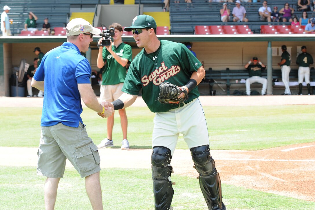 Lt. Col. Jason Hinds, 94th Fighter Squadron commander, shakes hands with Savannah Sand Gnats Catcher Xorge Carrillo after throwing out the ceremonial first pitch before the Sand Gnats' game July 22, 2012, in Savannah, Ga. Personnel from the 1st Fighter Wing are currently deployed to Savannah for training and exercises during the runway closure at Langley Air Force Base, Va.  (U.S. Air Force photo by 1st Lt. John Cooper/Released)