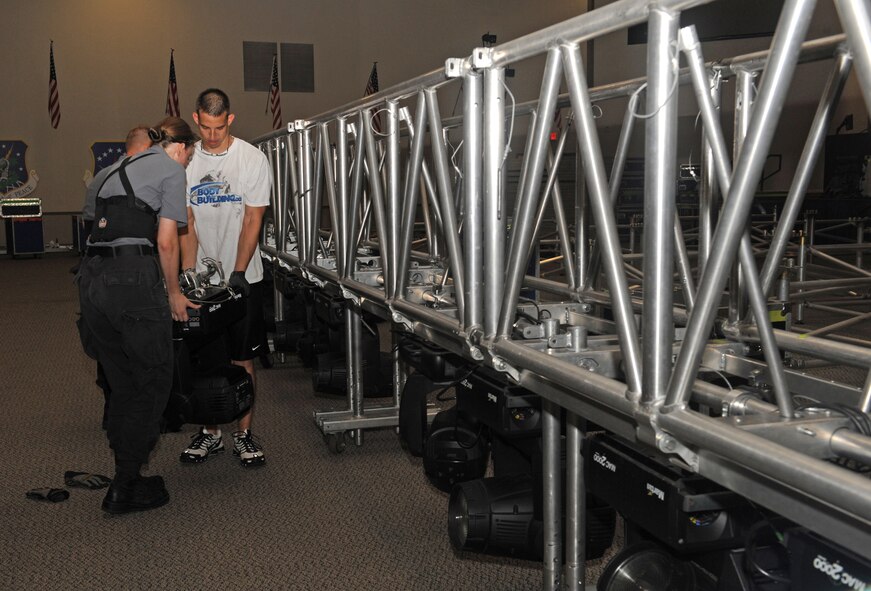 Senior Airman Ruth Bryce, Tops in Blue video director assigned to the 34th Combat Communications Squadron, Tinker Air Force Base, Okla., and Staff Sgt. Benjamin Farrell, 2nd Logistics Readiness Squadron, set up a light on a scaffold for the Tops in Blue performance at Barksdale AFB, La., Aug. 2. Tops in Blue is an active-duty unit consisting of the most talented vocalists, musicians, dancers and technicians in the Air Force. (U.S. Air Force photo/Airman 1st Class Benjamin Gonsier)(RELEASED)