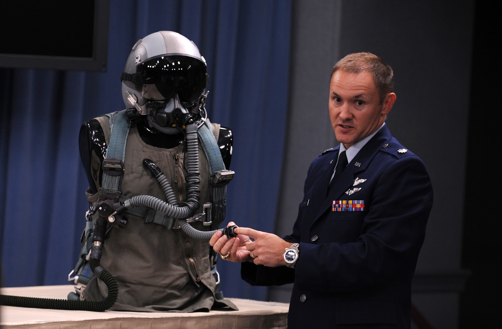Lt. Col. Jay Flottmann explains how a valve in the upper pressure garment and the shape and size of oxygen-delivery hoses and connection points contributed to previously unexplained physiological issues during F-22 Raptor flights. He spoke during a press conference in Washington, D.C., July 31, 2012. Flottmann is a flight surgeon and 325th Fighter Wing chief of flight safety. (U.S. Air Force photo/Senior Airman Christina Brownlow)