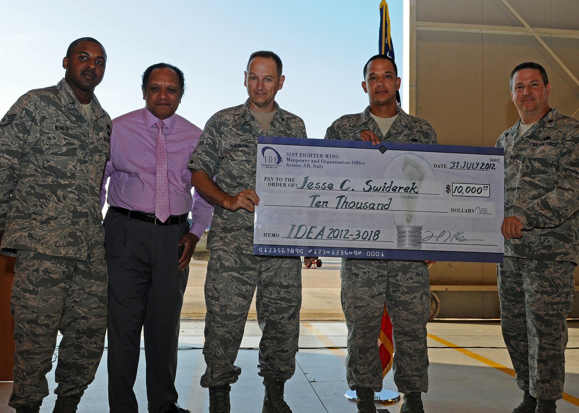 Tech. Sgt. Jesse Swiderek, 31st Maintenance Squadron aircraft metals technology craftsmen, (second from right) is presented a check for $10,000 from leadership and IDEA program managers July 31, during a commander's call on Aviano Air Base, Italy. The Innovative Development through Employee Awareness program provides a monetary incentive for members to submit ideas that streamline process and increase productivity and efficiency in the workplace.  (U.S. Air Force photo/Staff Sgt. Ryan Whitney)