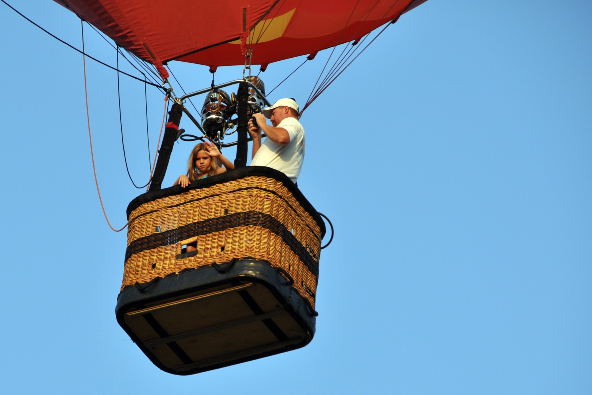 A little passenger in a hot air balloon waves at the crowd during the Ring Toss Competition of the Great Texas Balloon Race 2012, at the East Texas Regional Airport in Longview, Texas, July 28, 2012. For the first time in the 35-year history of the event, the U.S. National Championships were held in conjunction with the annual event. (U.S. Air Force photo by Master Sgt. Jeff Walston)    